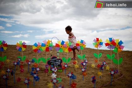 Bé gái Windan Palmer (2 tuổi) chạy đùa trên ngọn đồi chong chóng nơi được trang trí để tưởng niệm các nạn nhân trong vụ xả súng tại rạp chiếu phim ở bang Colorado, nước Mỹ