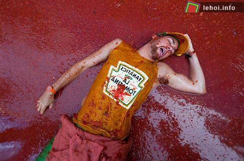 Trong khi có một anh chàng khác đang mặc chiếc áo in tên lễ hội Tomatina và thản nhiên nằm ngủ giữa biển nước cà chua. Tomatina là một lễ hội ném cà chua lớn nhất trên thế giới. Ảnh:   AFP