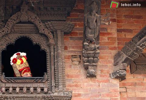 Một đứa trẻ trong trang phục nữ thần Kumari Devi đang nhìn qua ô cửa trước khi bước vào lễ hội Indrajatra tại Kathmandu. Cộng đồng Newar của Nepal thường tổ chức lễ hội Indrajatra để cầu thánh Kumari và cầu thần mưa Indra. 