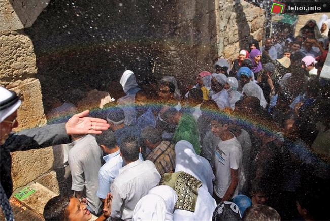 Xuất hiện cầu vồng khi một người Palestin vẩy nước lên các tín đồ Hồi giáo để làm mát khi họ chuẩn bị rời khỏi nhà thờ Al Aqsa tại Jerusalem .